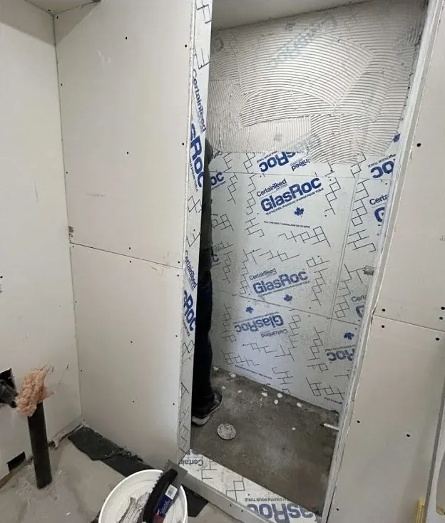 An unfinished shower stall lined with glass-mat backer board.