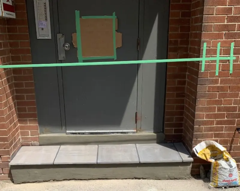 The same doorway with a new, level step capped in grey pavers.